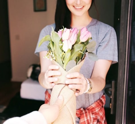 Frau bekommt Blumenstrauß zu Valentinstag geschenkt
